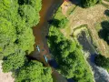 Spływ kajakowy malowniczą rzeką to jedna z wielu atrakcji Kociewia. Dwie kajaki płyną wśród bujnej zieleni.