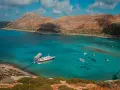 Wycieczka na Santorini z Krety: statki cumują w turkusowej zatoce, otoczonej skalistymi wzgórzami.
