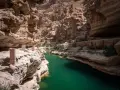 Wadi Shab w Omanie, z turkusową wodą i skalnymi ścianami, to jedna z wielu atrakcji tego kraju. Oman ciekawostki.