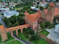 Zamek w Kwidzynie, z charakterystycznym gdaniskiem i mostem, otoczony zielenią i zabudowaniami. Ciekawostki o zamku czekają na odkrycie!