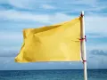 Żółta flaga na plaży oznacza umiarkowane zagrożenie. Woda jest bezpieczna do kąpieli, ale należy zachować ostrożność.