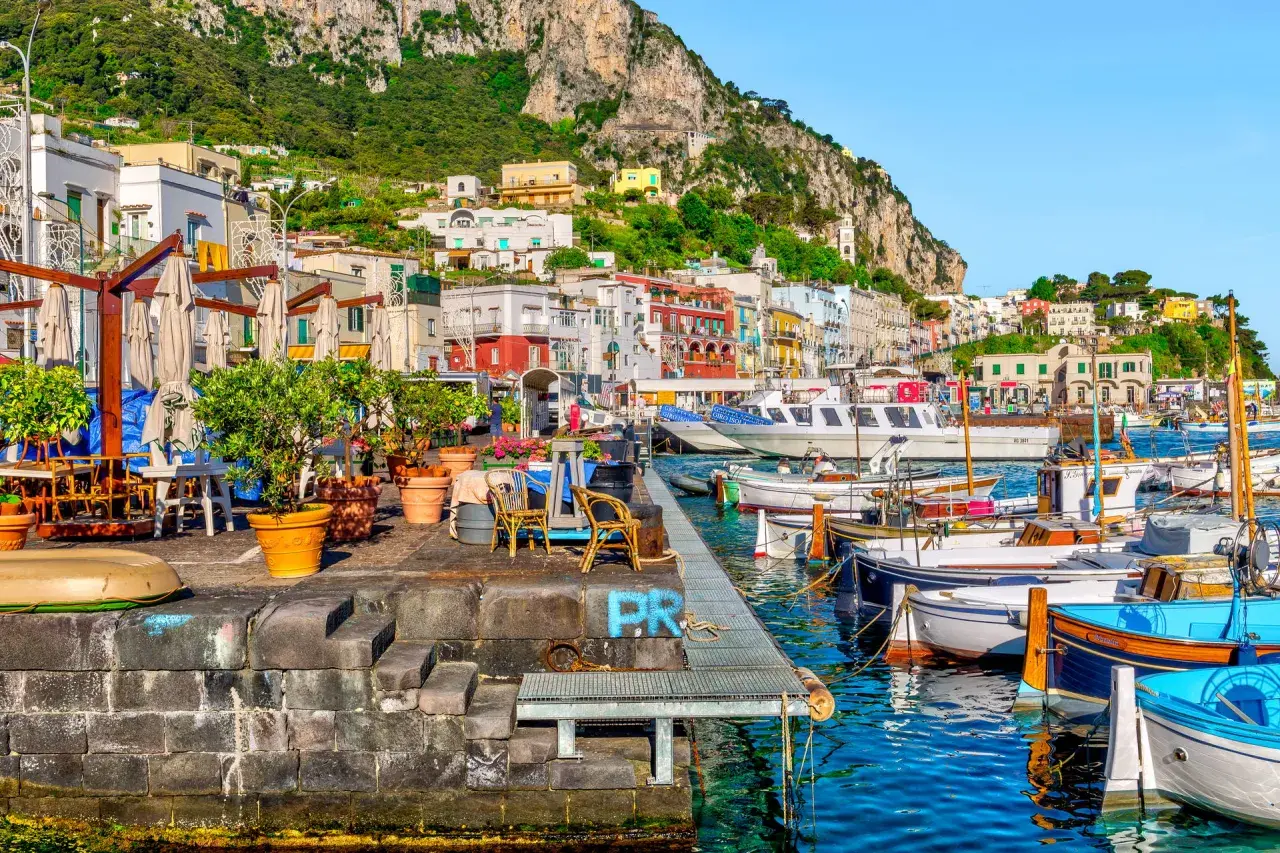 Port na Capri, z kolorowymi budynkami i łodziami, idealne miejsce na wakacje all inclusive.