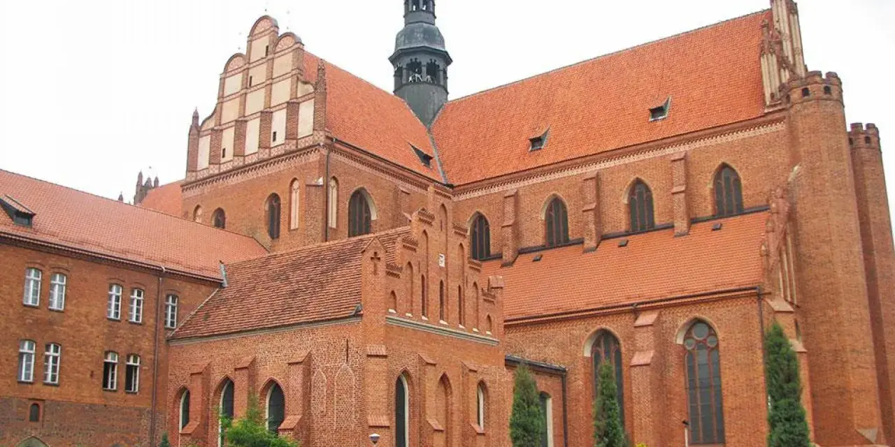 Gotycka katedra w Pelplinie, dawniej część kompleksu zamkowego, z charakterystycznymi ceglanymi murami i czerwonymi dachami.
