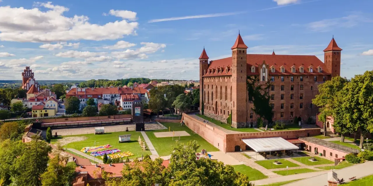 Zamek w Gniewie zaprasza na zwiedzanie. Potężna ceglana budowla z czerwonym dachem i wieżyczkami góruje nad miastem.