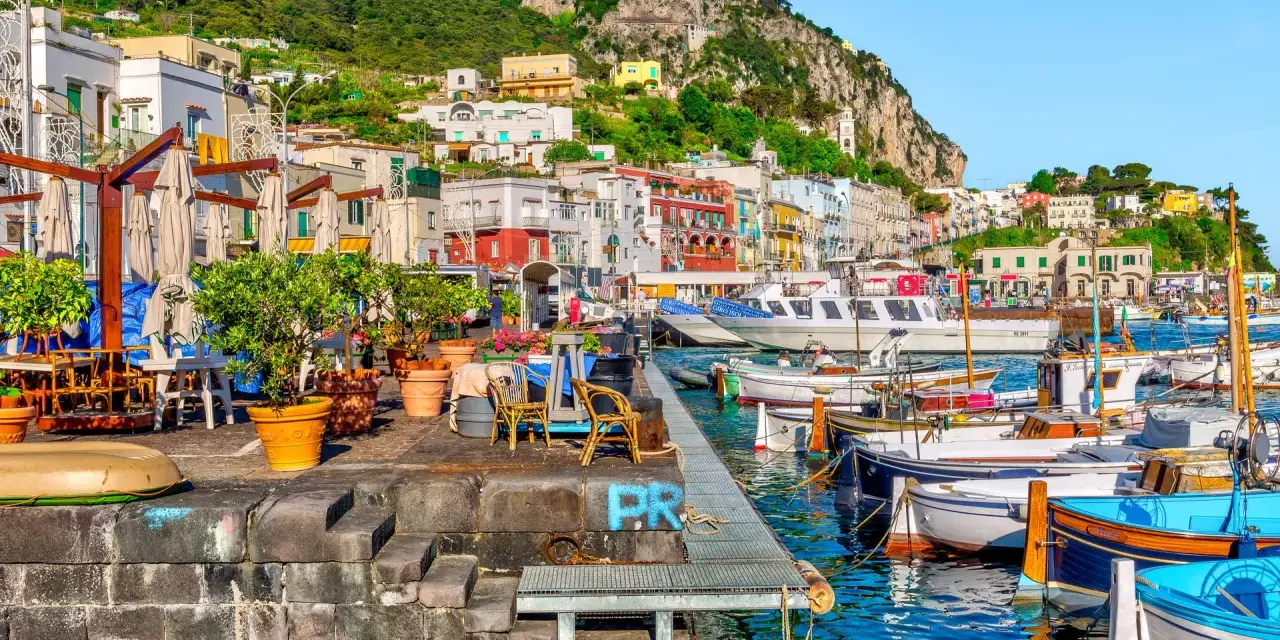 Port na Capri, z kolorowymi budynkami i łodziami, idealne miejsce na wakacje all inclusive.