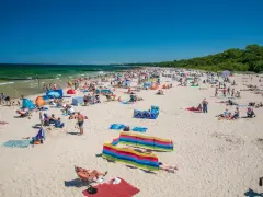 Tłum ludzi cieszy się słońcem na piaszczystej plaży. Woda w Bałtyku jest turkusowa, a niebo bezchmurne. To obrazek z jednych z najpiękniejszych plaż nad Bałtykiem.
