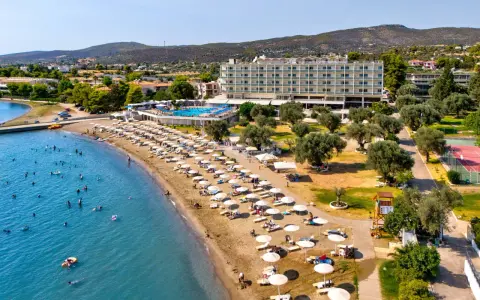 Piękna plaża na Evii, idealna na wycieczki fakultatywne. Hotel, basen, leżaki i mnóstwo ludzi kąpiących się w morzu.