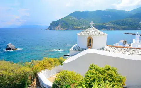 Malownicza zatoka i białe kościółki na wzgórzu. Idealne miejsce na skopelos wakacje.