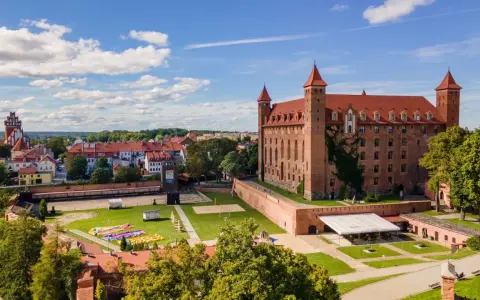 Zamek w Gniewie zaprasza na zwiedzanie. Potężna ceglana budowla z czerwonym dachem i wieżyczkami góruje nad miastem.
