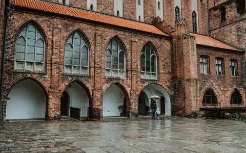 Zamek w Kwidzynie zaprasza. W deszczowy dzień zwiedzający z parasolem podziwiają gotycką architekturę. Bilety dostępne online.