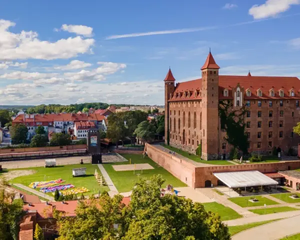 Zamek w Gniewie zaprasza na zwiedzanie. Potężna ceglana budowla z czerwonym dachem i wieżyczkami góruje nad miastem.
