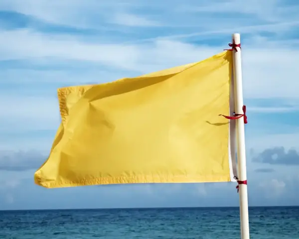 Żółta flaga na plaży oznacza umiarkowane zagrożenie. Woda jest bezpieczna do kąpieli, ale należy zachować ostrożność.