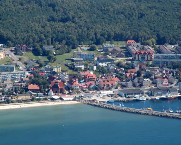 Widok na nadmorskie miasto Hel z portem, plażą i zabudowaniami.