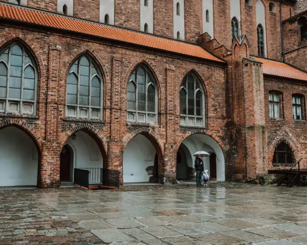 Zamek w Kwidzynie zaprasza. W deszczowy dzień zwiedzający z parasolem podziwiają gotycką architekturę. Bilety dostępne online.