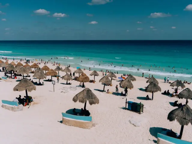 Słoneczny dzień na plaży w Meksyku. Ludzie odpoczywają pod strzechami, kąpią się w turkusowym morzu. Idealne wakacje!