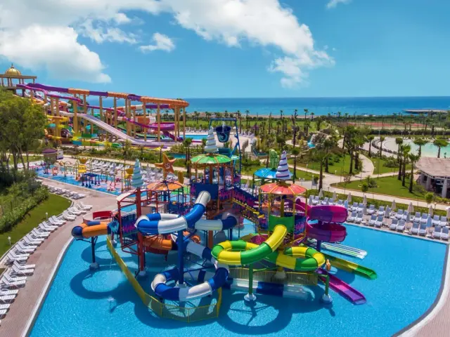 Kolorowy aquapark z licznymi zjeżdżalniami i basenami, idealny dla rodzin szukających rozrywki w luksusowych riwiera turecka hotele 5-gwiazdkowe.