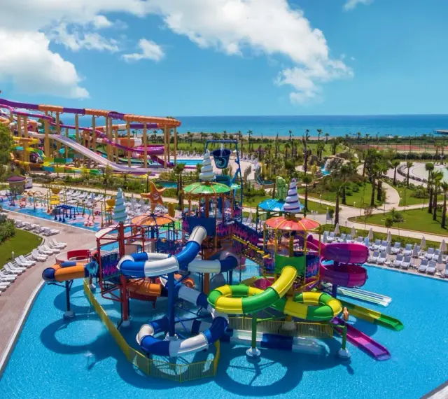 Kolorowy aquapark z licznymi zjeżdżalniami i basenami, idealny dla rodzin szukających rozrywki w luksusowych riwiera turecka hotele 5-gwiazdkowe.