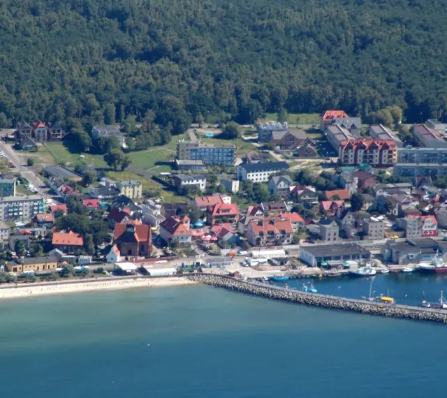 Widok na nadmorskie miasto Hel z portem, plażą i zabudowaniami.