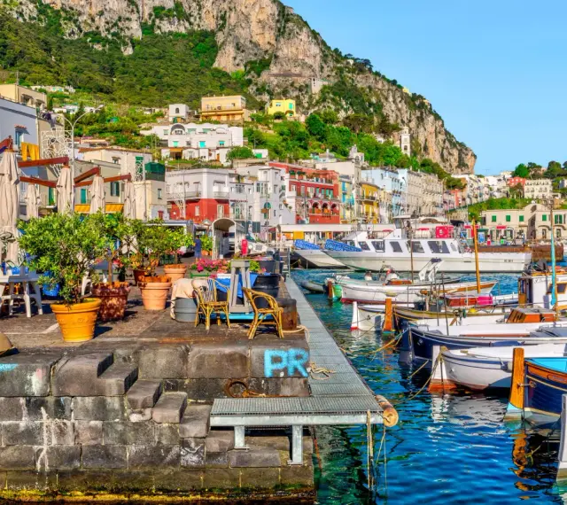 Port na Capri, z kolorowymi budynkami i łodziami, idealne miejsce na wakacje all inclusive.