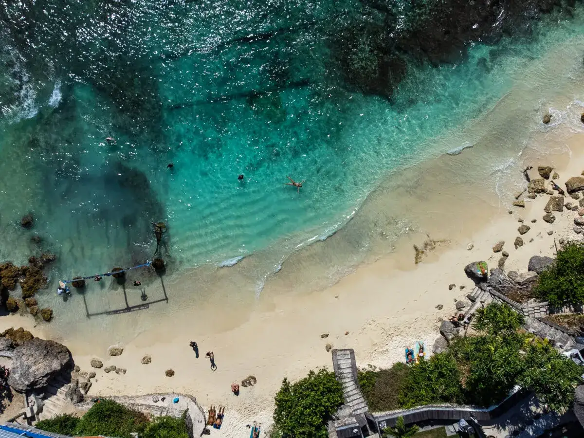 Wycieczka na Bali: turkusowa woda, piaszczysta plaża i ludzie relaksujący się na słońcu.