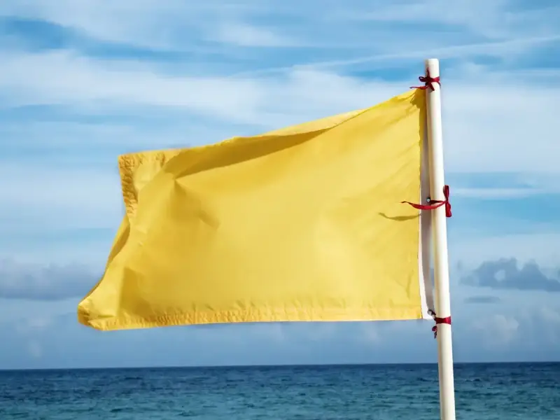 Żółta flaga na plaży oznacza umiarkowane zagrożenie. Woda jest bezpieczna do kąpieli, ale należy zachować ostrożność.